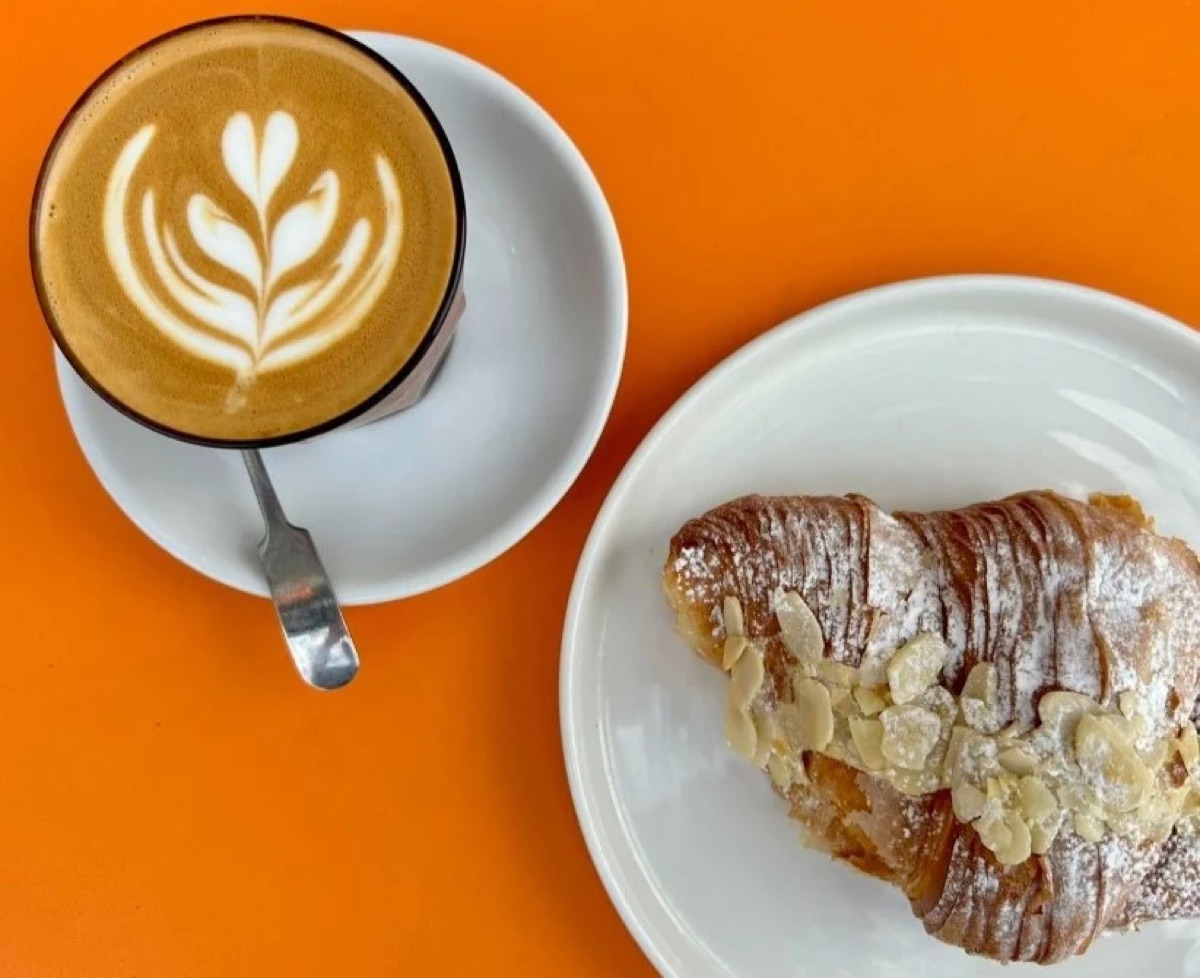 Latte with leaf art and an almond croissant